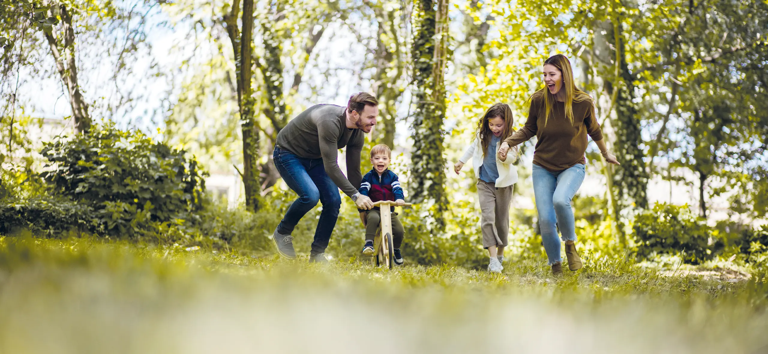 Junge Familie spielt mit ihren 2 Kindern im Stadtgarten